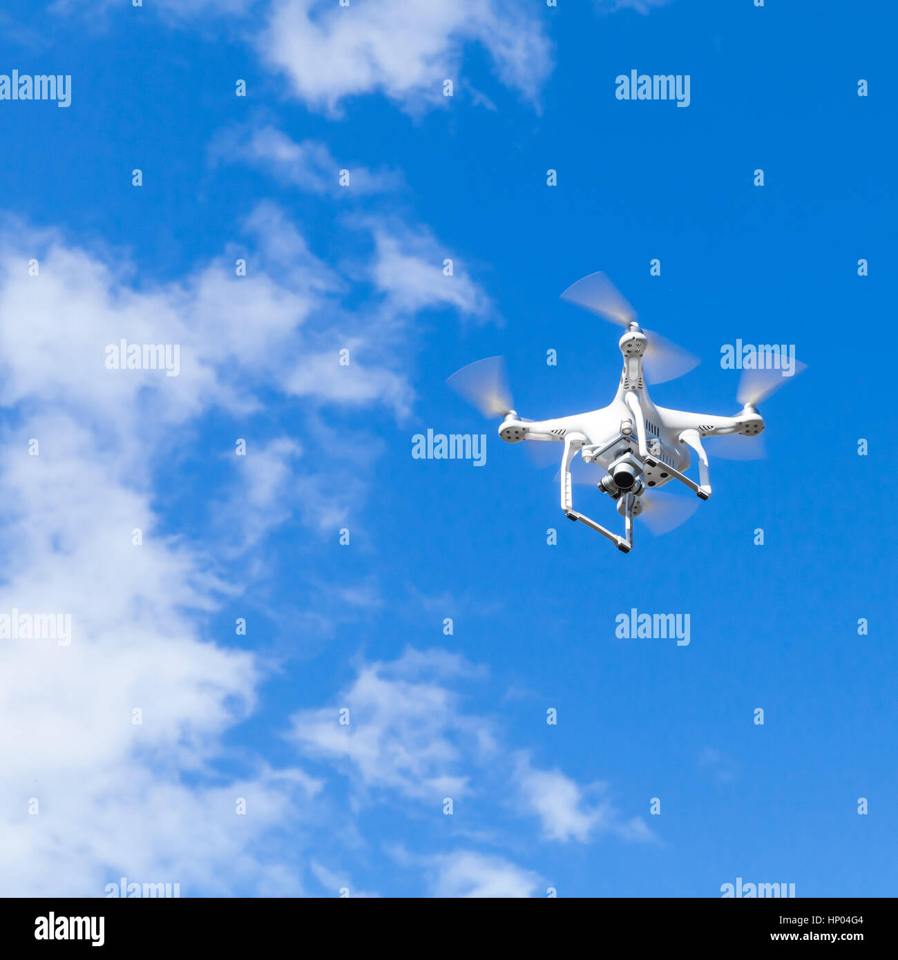 White quadrocopter in cielo molto nuvoloso, compatto drone controllato dal telecomando wireless Foto Stock