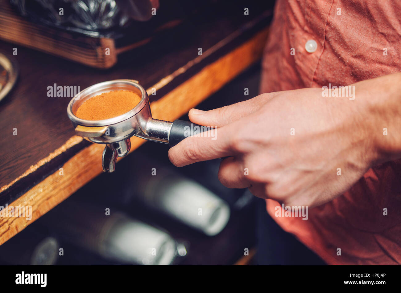 Primo piano della mano con i baristi titolare con caffè appena macinato. Soft focus Foto Stock