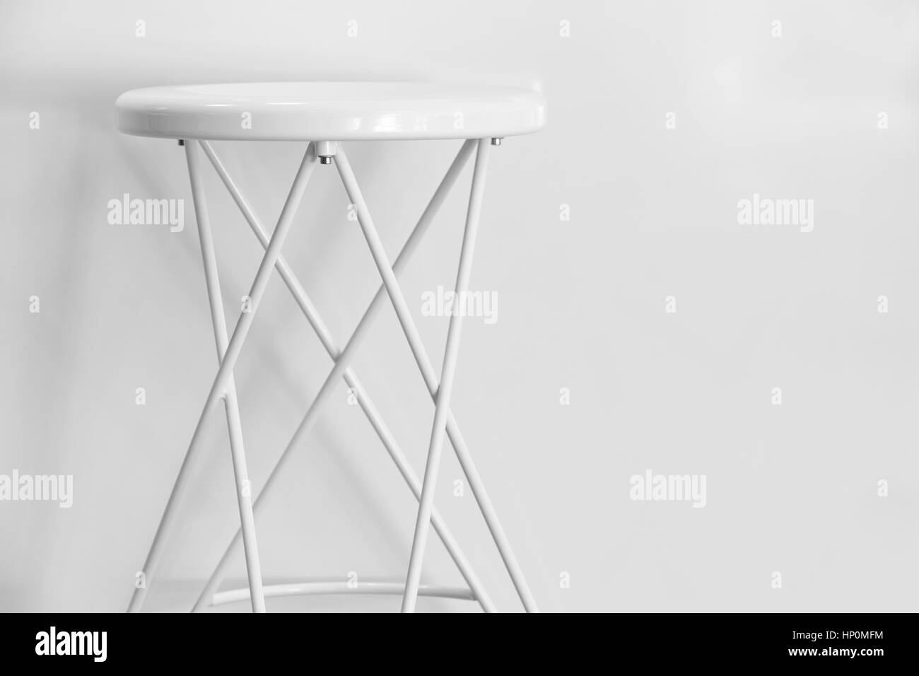 Bianco sgabello metallico su una parete bianca. Copia dello spazio. Posizione orizzontale Foto Stock