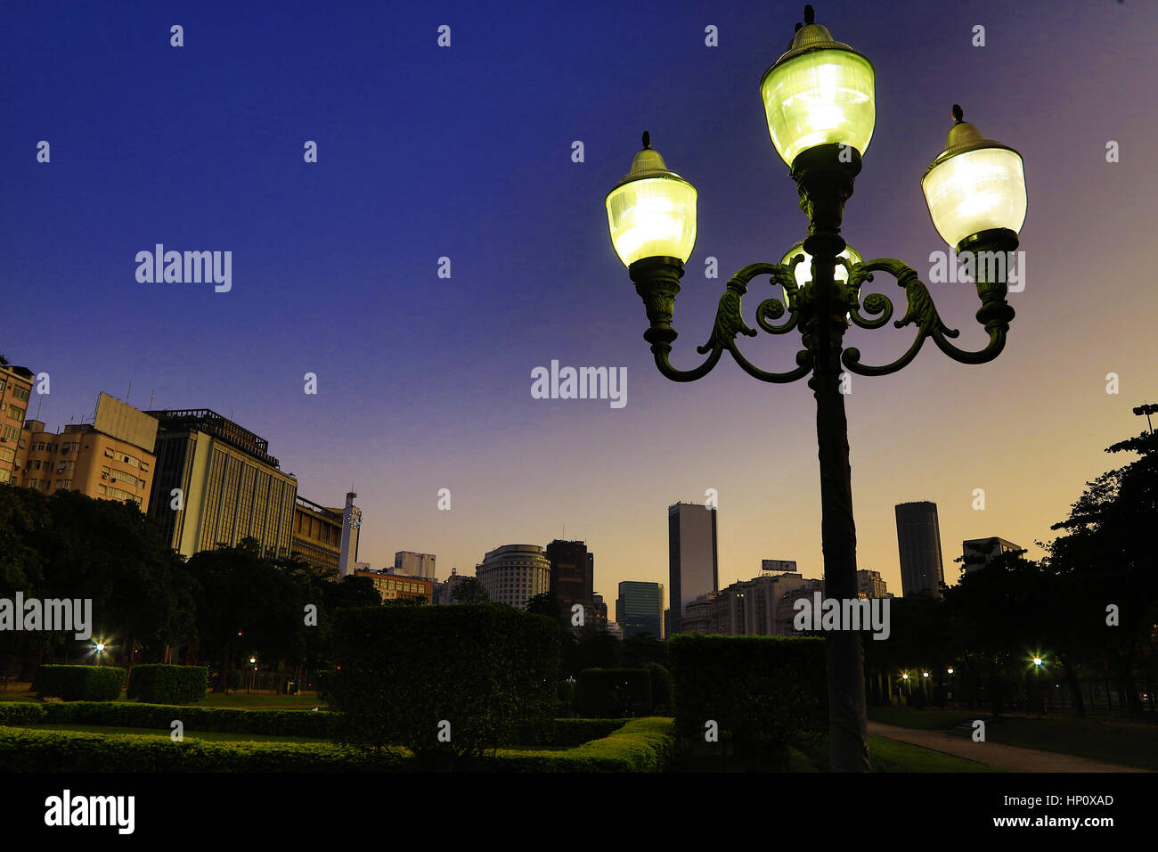 Sunrise in Rio de Janeiro Praça Paris, con city center edifici in background. Il vecchio stile illuminazione sul primo piano, Rio de Janeiro, Brasile Foto Stock