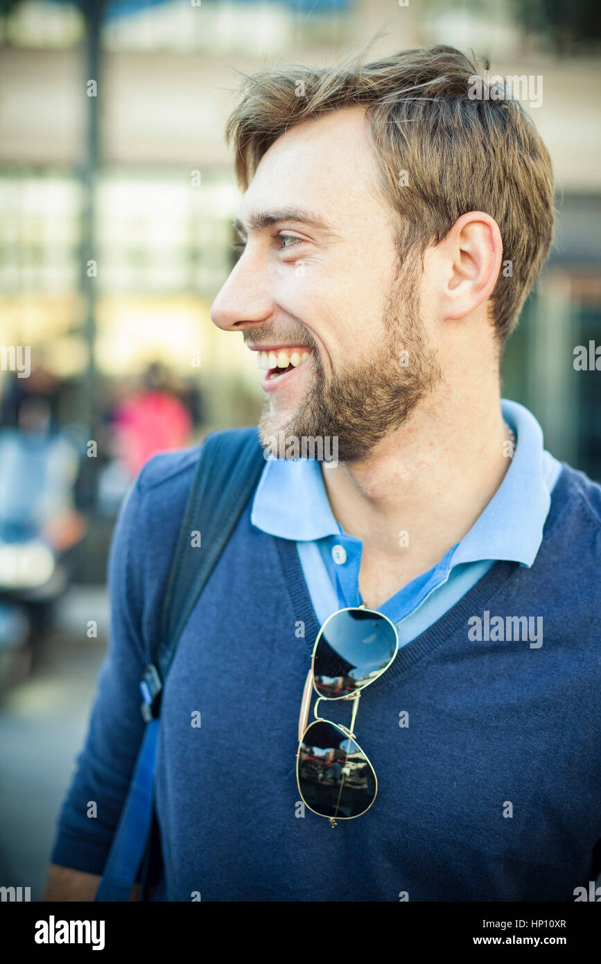 Giovane uomo che guarda lontano e sorridendo allegramente Foto Stock