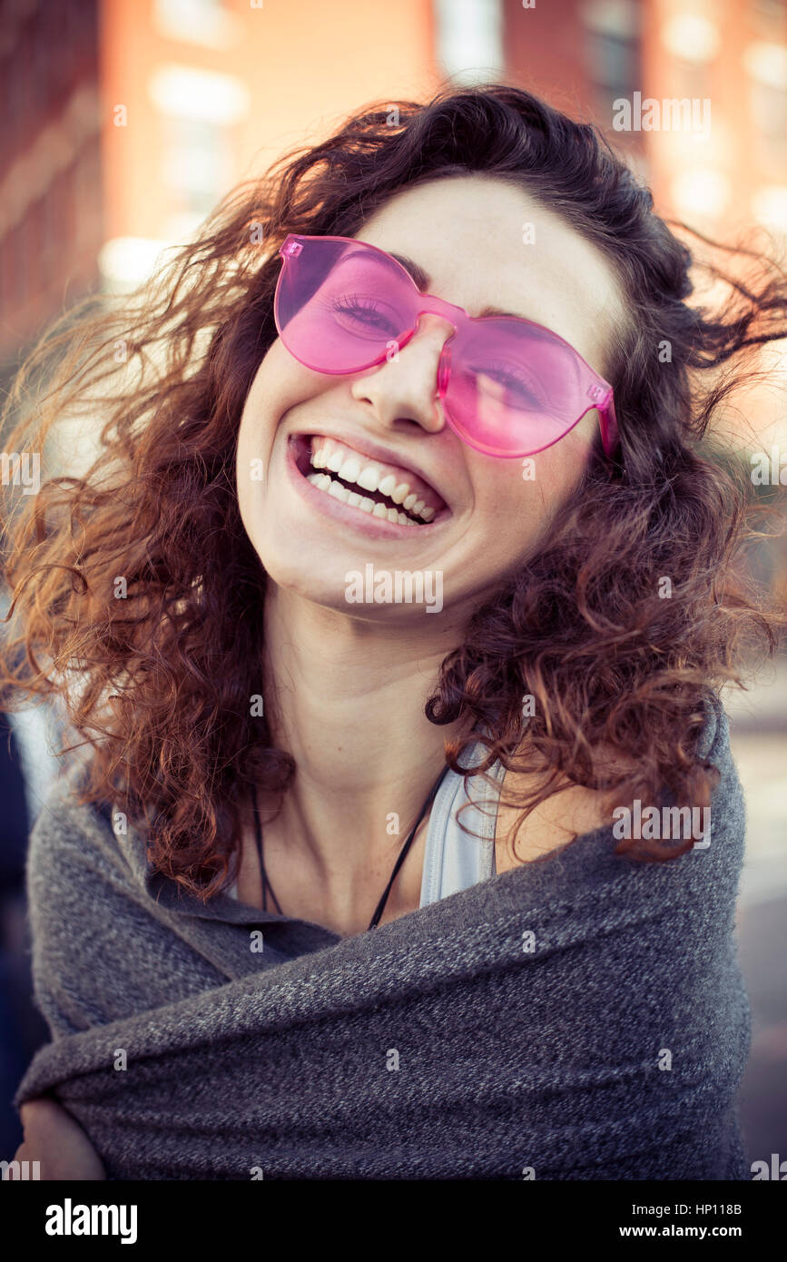 Donna che indossa gli occhiali da sole rosa, ridendo, ritratto Foto Stock