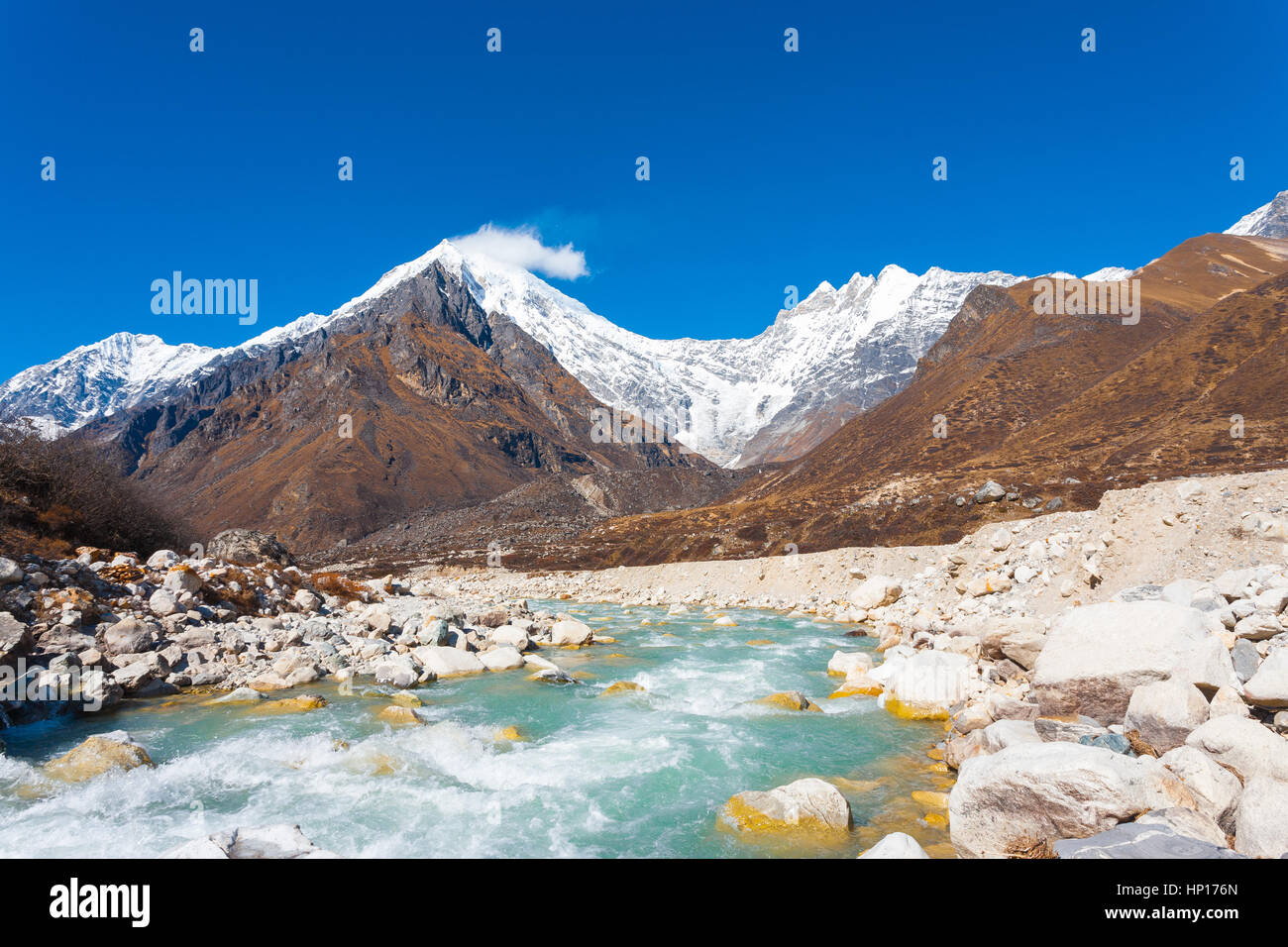 Vista del paesaggio di Langtang Lirung peak, parte di snow-capped Himalaya Mountain Range dietro a scorrimento veloce glaciale del fiume di acqua ad elevata altitudine in Nepal. Foto Stock