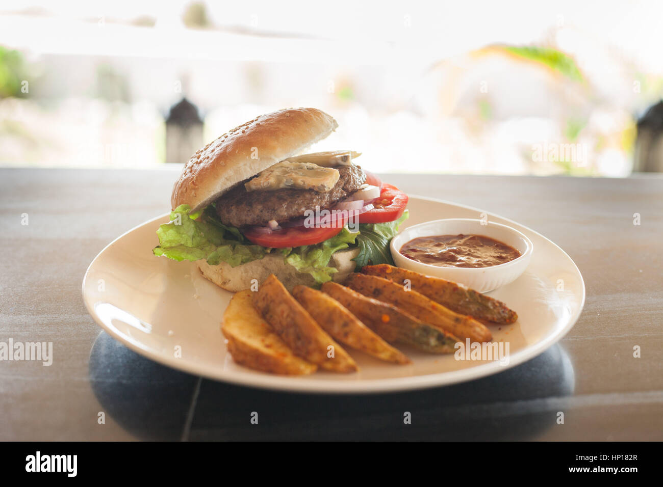 Un bleu (blu) del formaggio hamburger con patatine e salsa barbecue su un piano portapaziente ardesia Foto Stock