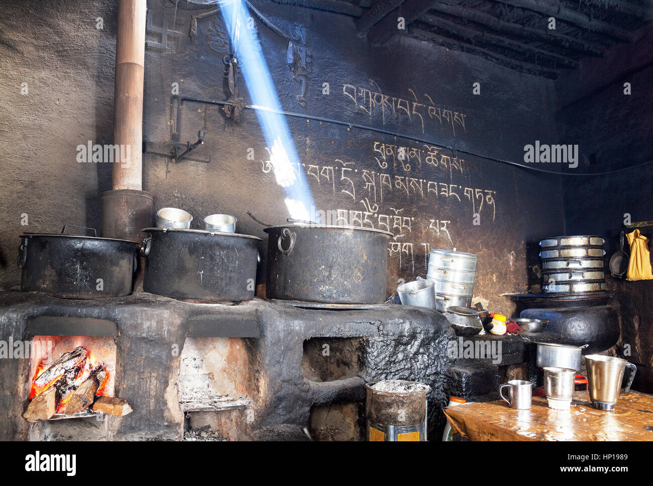 Monastero di chiave, India - 28 Aprile 2016: un raggio di sole risplende attraverso il camino creano atmosfera sublime in cucina- hall di un antico Bud Foto Stock