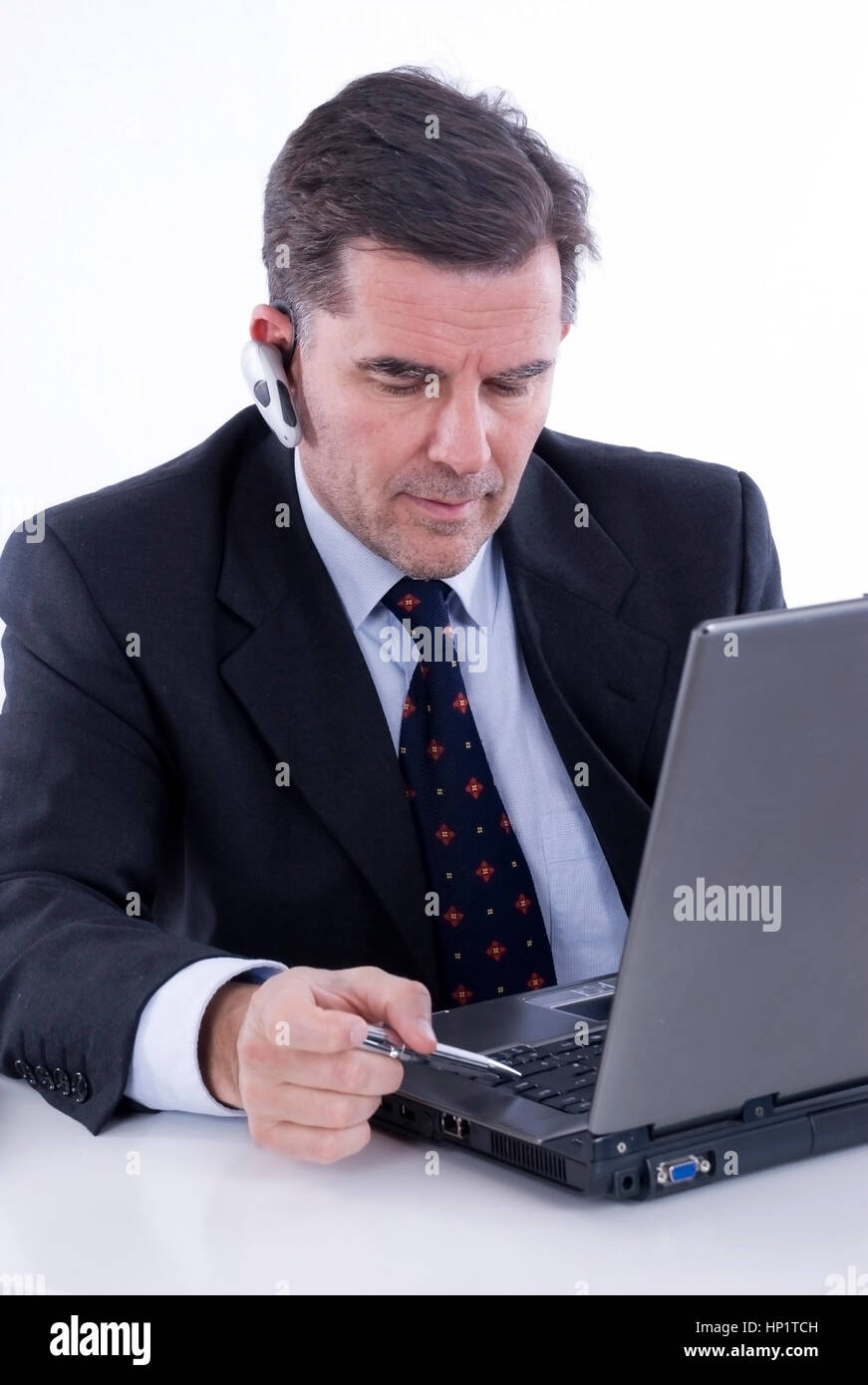 Geschaeftsmann, 50+, bei der Arbeit am Laptop mit dente blu - imprenditore in ufficio Foto Stock