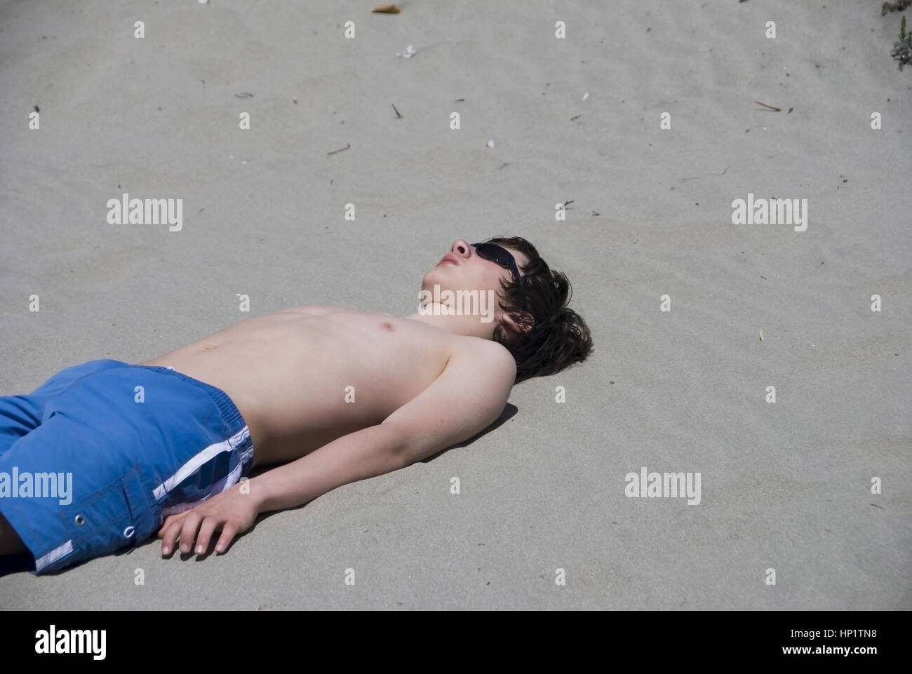Jugendlicher liegt im Sand am Strand und sonnt sich - teenager suns in spiaggia Foto Stock