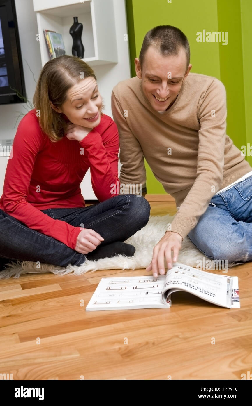 Modello di rilascio , Paar betrachtet gemeinsam Versandhauskatalog - giovane guardando mail-Ordinazione catalogo Foto Stock