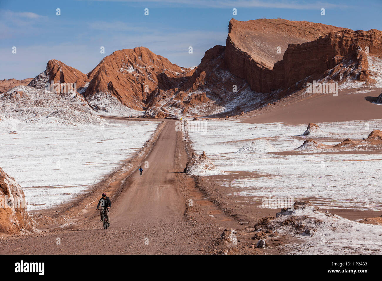 Ciclismo, pista, strada, di fronte alla Valle de la Luna (Valle della Luna) e sale depositato sul terreno, deserto Atacama. Regione di Antofagasta. Cile Foto Stock