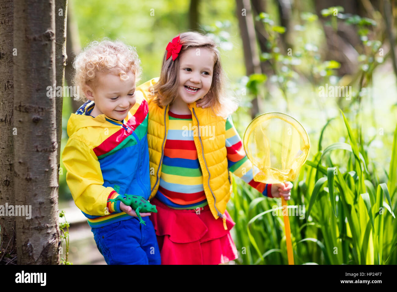 Bambini che giocano all'esterno. I bambini di età prescolare la cattura di rana con net. Un ragazzo e una ragazza la pesca nel fiume della foresta. Avventura kindergarten escursione di un giorno in una selvaggia natu Foto Stock