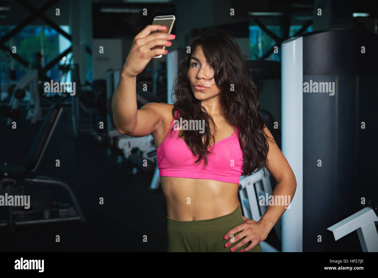 Ragazza in posa per selfie in palestra prendendo con moderni smartphone nel fitness club sfondo Foto Stock