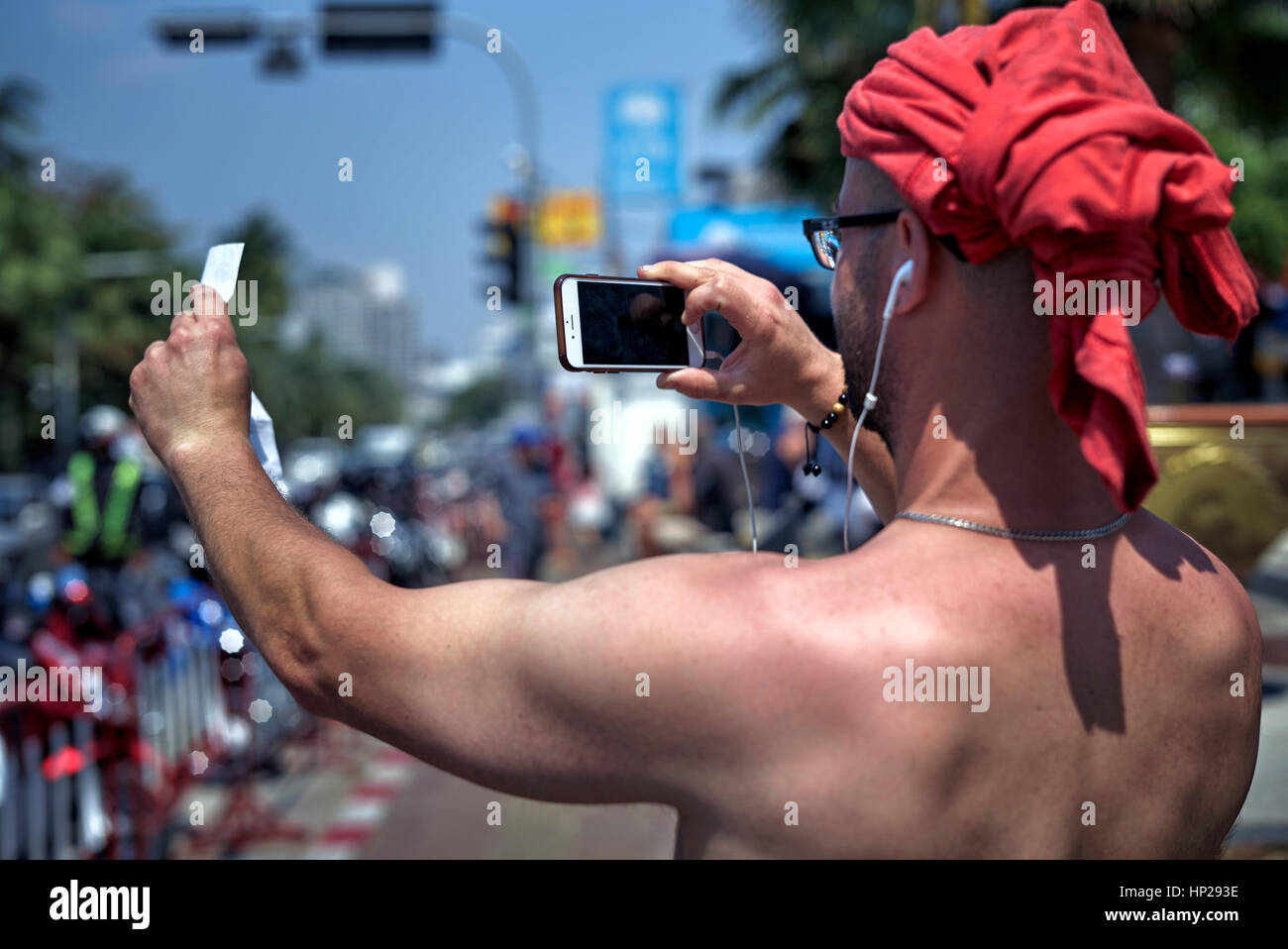 Turista thailandese, scattando una fotografia con il suo smartphone, con T-shirt adattato come protezione del sole della testa. Tecnologia di comunicazione Foto Stock