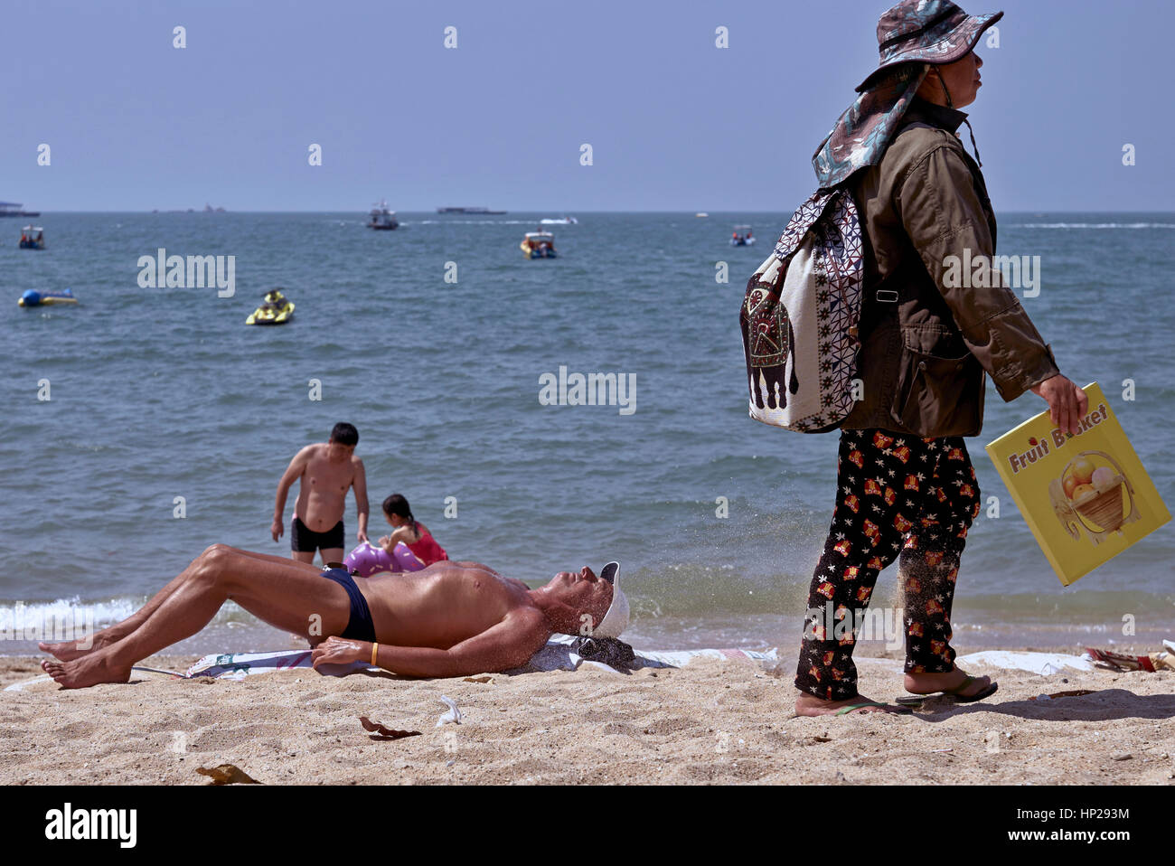 Turismo a maschio a prendere il sole sulla spiaggia di Pattaya Thailandia con passaggio di fornitore di bevande. Foto Stock