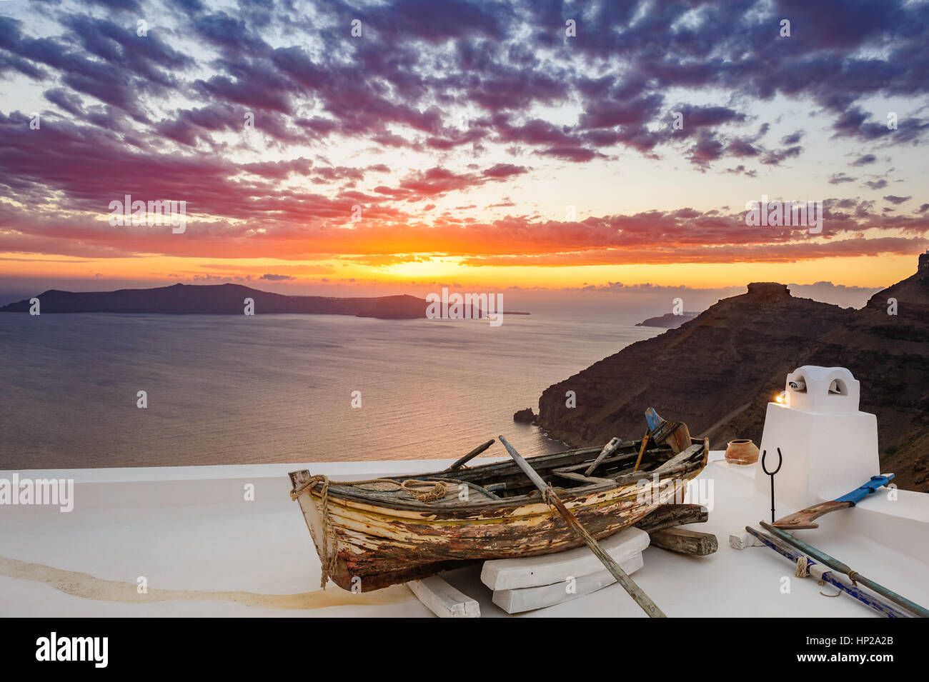 In legno antico fishermans''s barca su roofof house di Firostefani village con la tipica architettura di bianco, isola di Santorini, Grecia, durante il tramonto sul mare Foto Stock