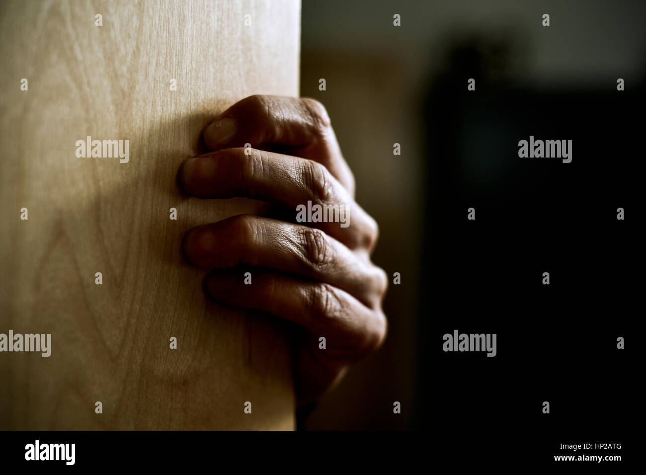 Primo piano della mano di un giovane uomo caucasico fuoruscita fortemente da dietro una porta Foto Stock