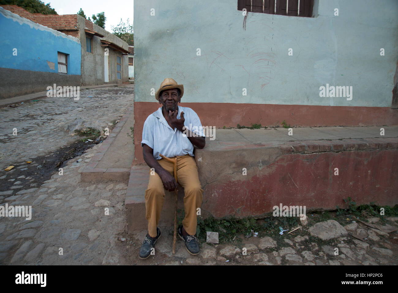 Un vecchio uomo cubano indossando un cappello di paglia si trova all'angolo di una strada in Trinidad, Cuba Foto Stock
