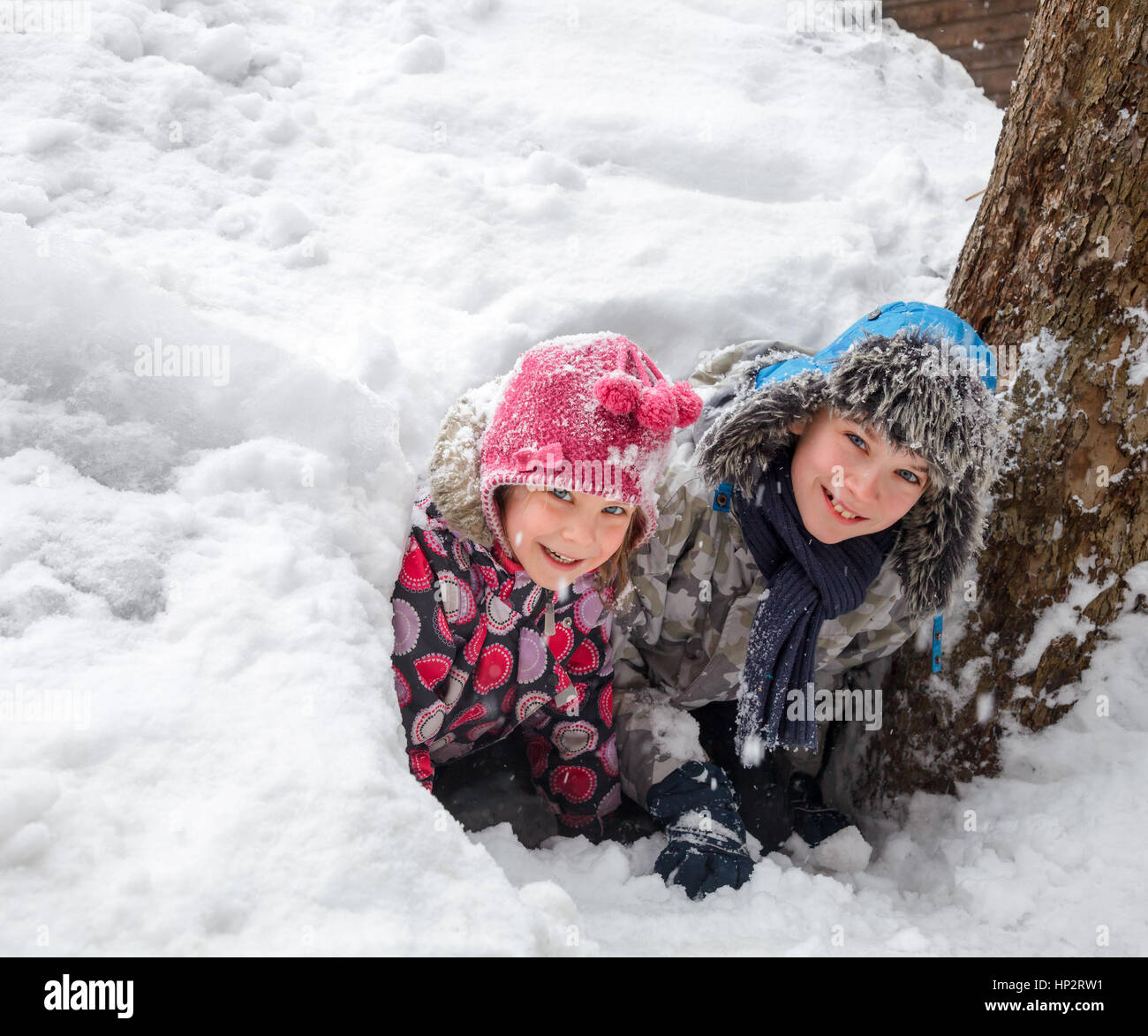 Felice un ragazzo e una ragazza che guarda fuori da una grotta di neve hanno reso in un cumulo di neve Foto Stock