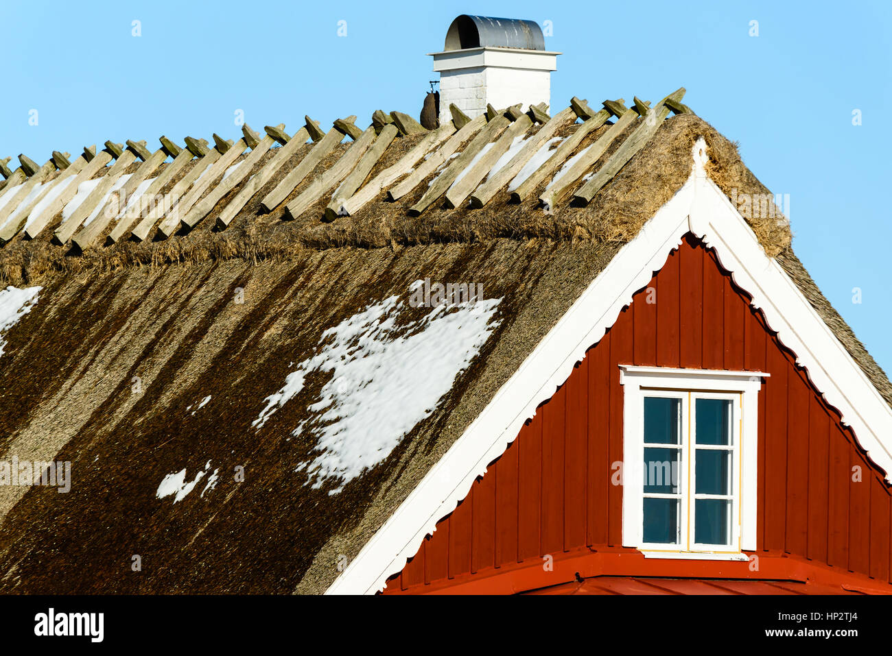 Close up di scongelamento di neve sul tetto di paglia sulla casa rossa. Foto Stock