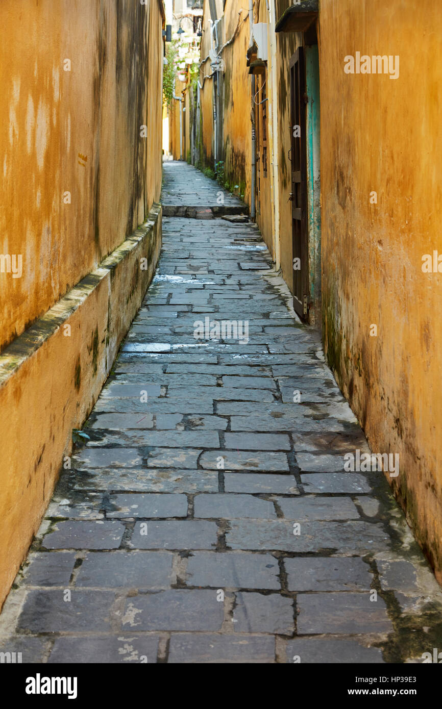 Ciottoli e pareti gialle in vicolo, Hoi An (Patrimonio Mondiale dell'UNESCO), Vietnam Foto Stock