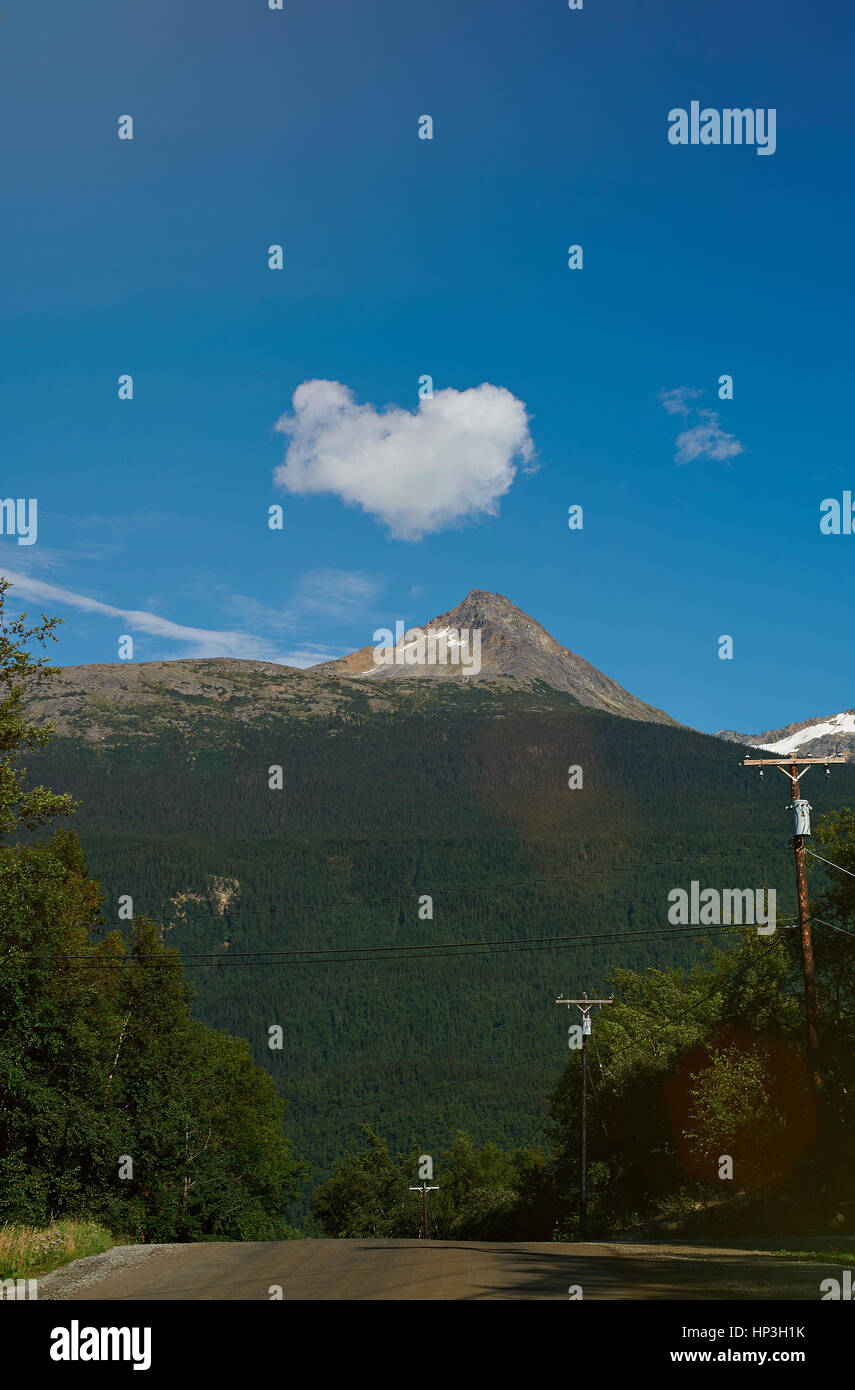 Forma di cuore il cloud sotto il paesaggio di montagna. Strada con il cloud cuore blu cielo Foto Stock