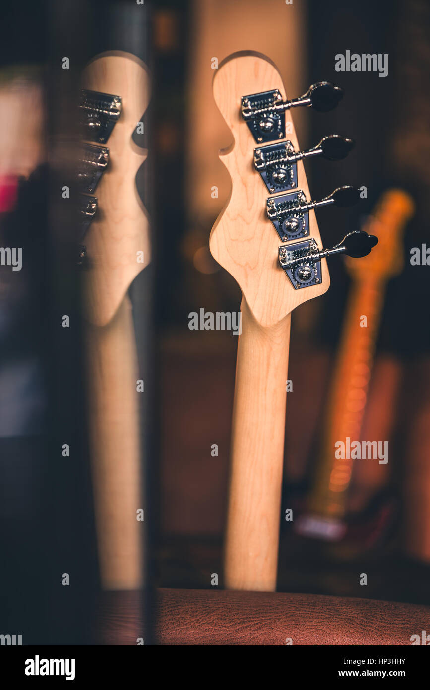 Dettaglio della chitarra basso della testa e del collo con la riflessione. Altri colli di chitarra in background. Filtro vintage. Bass Guitar ancora in vita. Musica di sottofondo. Foto Stock