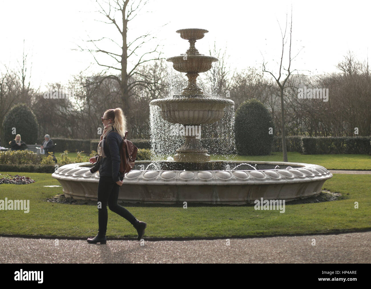 Una donna cammina davanti ad una fontana in Regent's Park di Londra, come un soffio di aria calda dalle Americhe porta più mite clima per il Regno Unito. Foto Stock