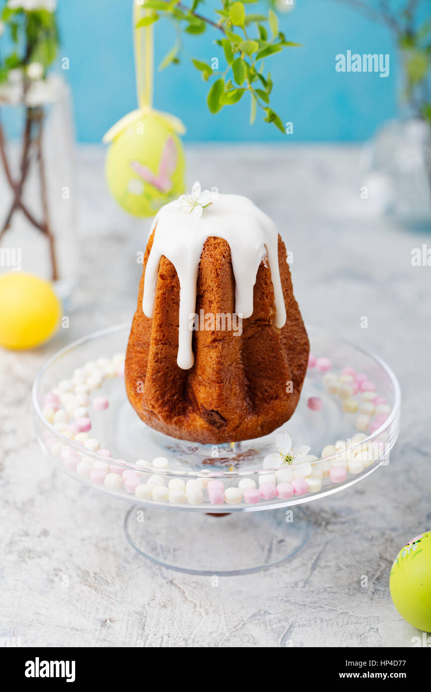 Tradizionale torta di Pasqua con uova colorate e fiori. Sfondo blu Foto Stock