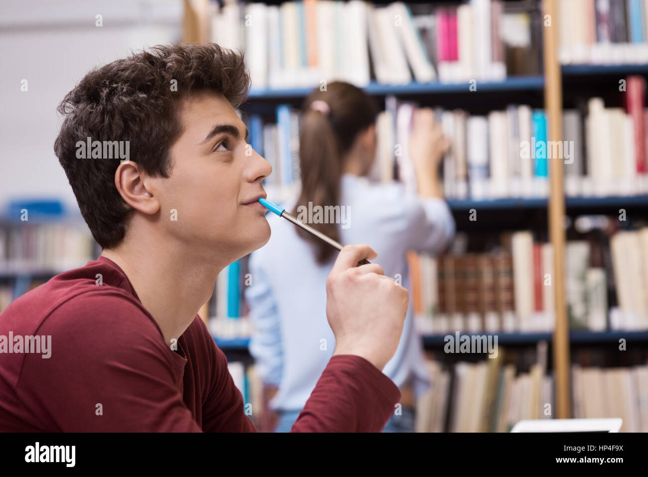 Giovane studente studiare in biblioteca, ragazza e scaffali su sfondo Foto Stock