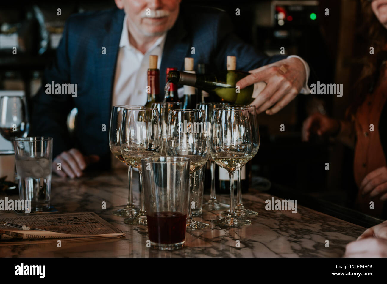 L'uomo pourign bicchieri di vino bianco per le persone. Foto Stock