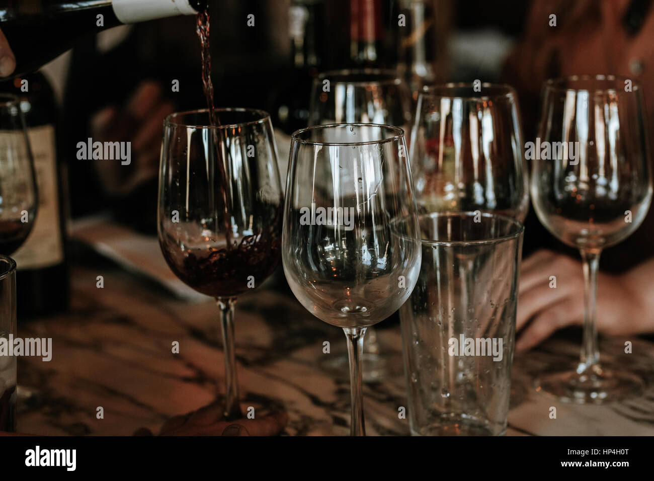 Vino rosso che viene colato con occhiali altri. Foto Stock