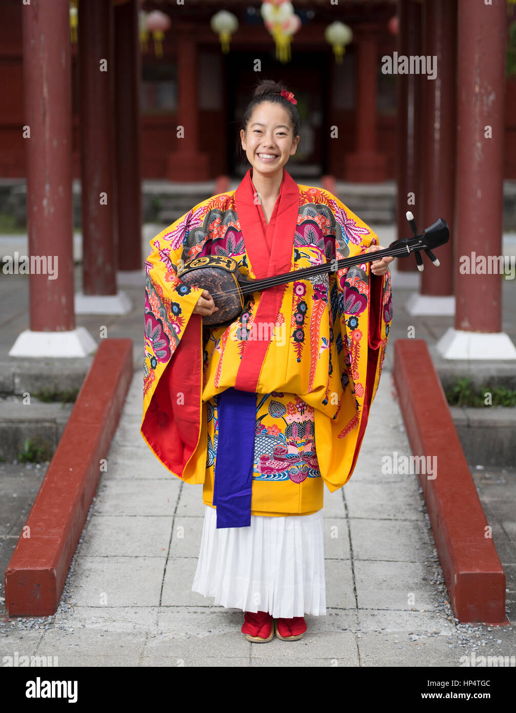 Okinawa musicista Nayuta Hirano con sanshin (strumento) e tradizionale ryuso Okinawa kimono a Murasaki Mura, Yomitan, Okinawa Foto Stock