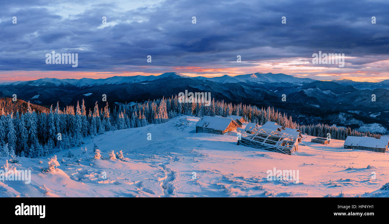 Fantastico tramonto su montagne innevate e chalets in legno. Foto Stock