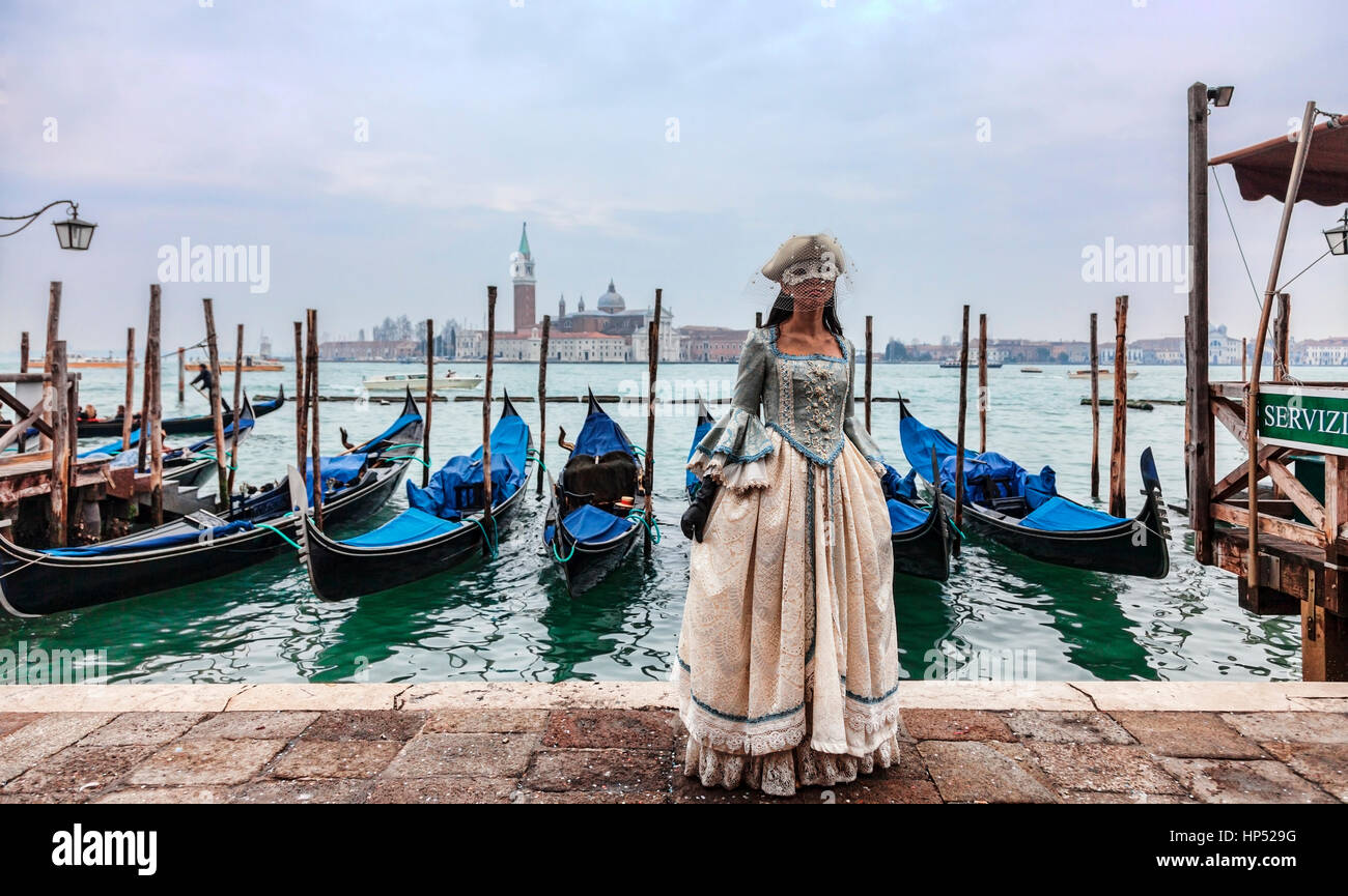 Venezia, Italia- Febbraio 198th, 2012:Una donna ina bel vestito e colombina maschera in posa di fronte di gondole durante il Carnevale di Venezia. Foto Stock