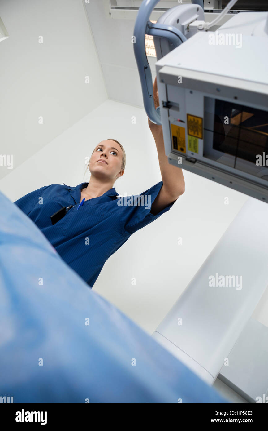 Basso angolo vista del radiologo regolazione macchina xray su paziente Foto Stock