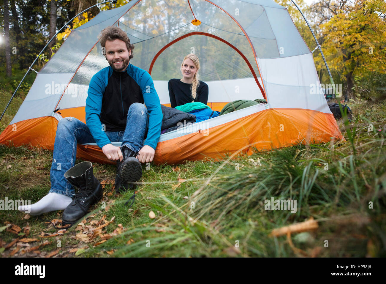 Uomo che indossa il boot mentre donna rilassante in tenda Foto Stock