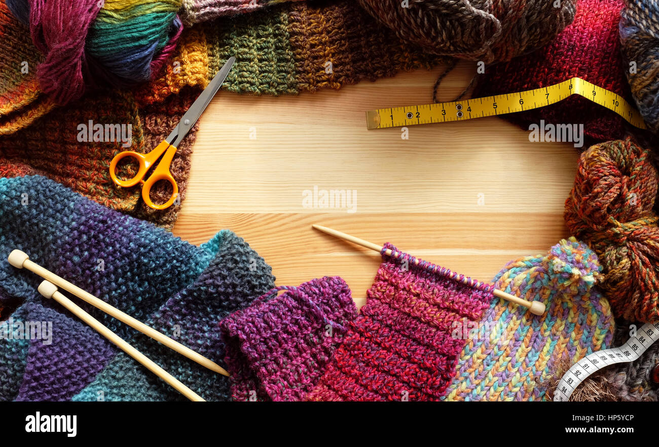 Confine di maglieria colorata, lana e accessori artigianali su sfondo di legno Foto Stock