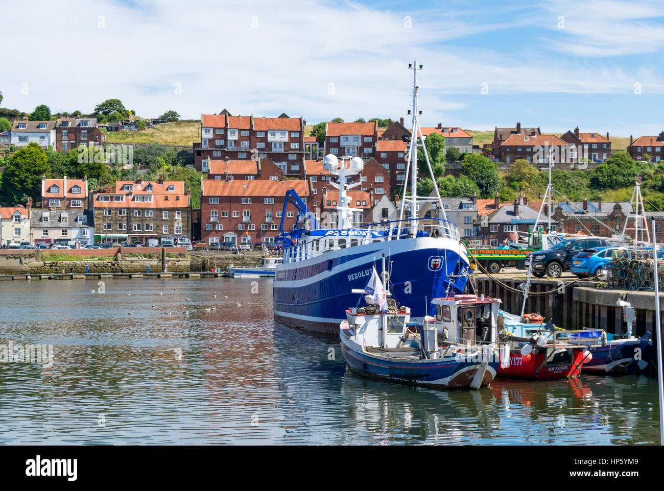 Ormeggiate barche da pesca nel porto di Whitby con case in background, North Yorkshire, Regno Unito Foto Stock