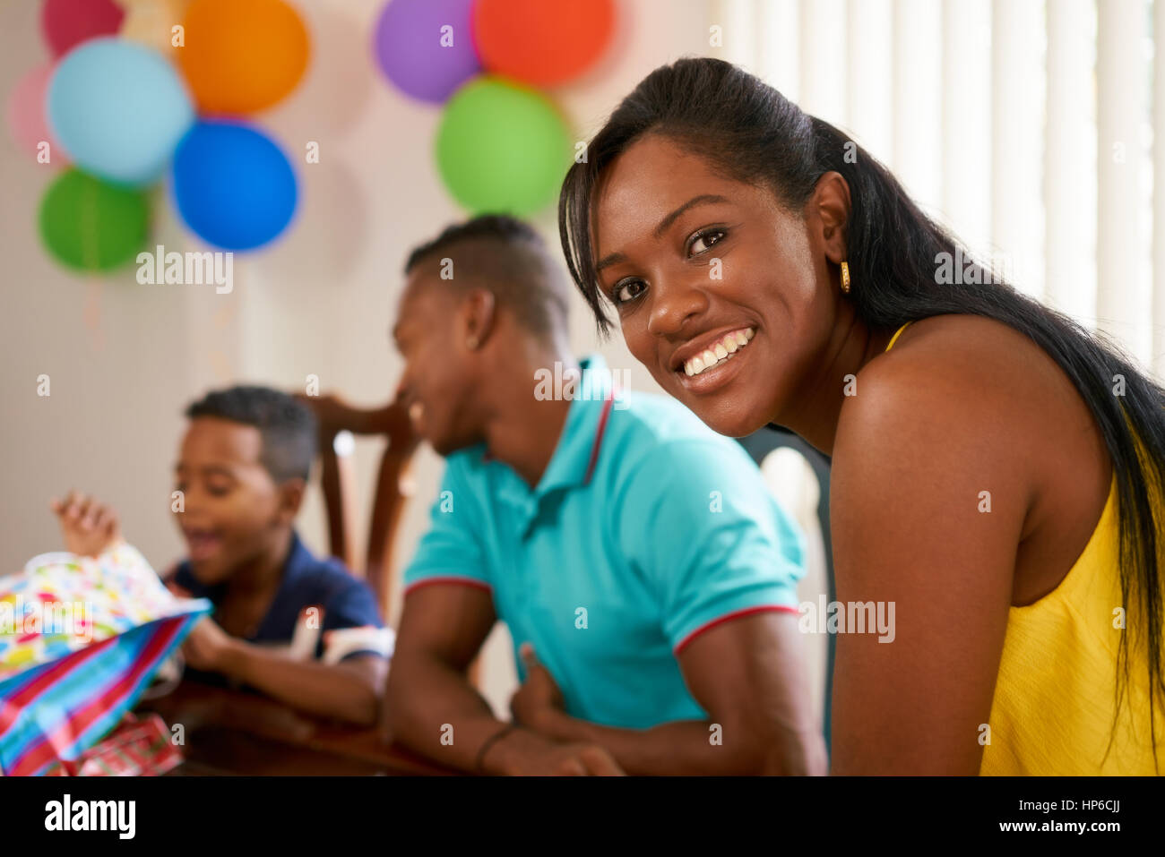 Felice famiglia nero a casa. African American padre, madre e bambino festeggia il compleanno, divertendosi a parte. Ritratto di giovane donna sorridente a ca Foto Stock