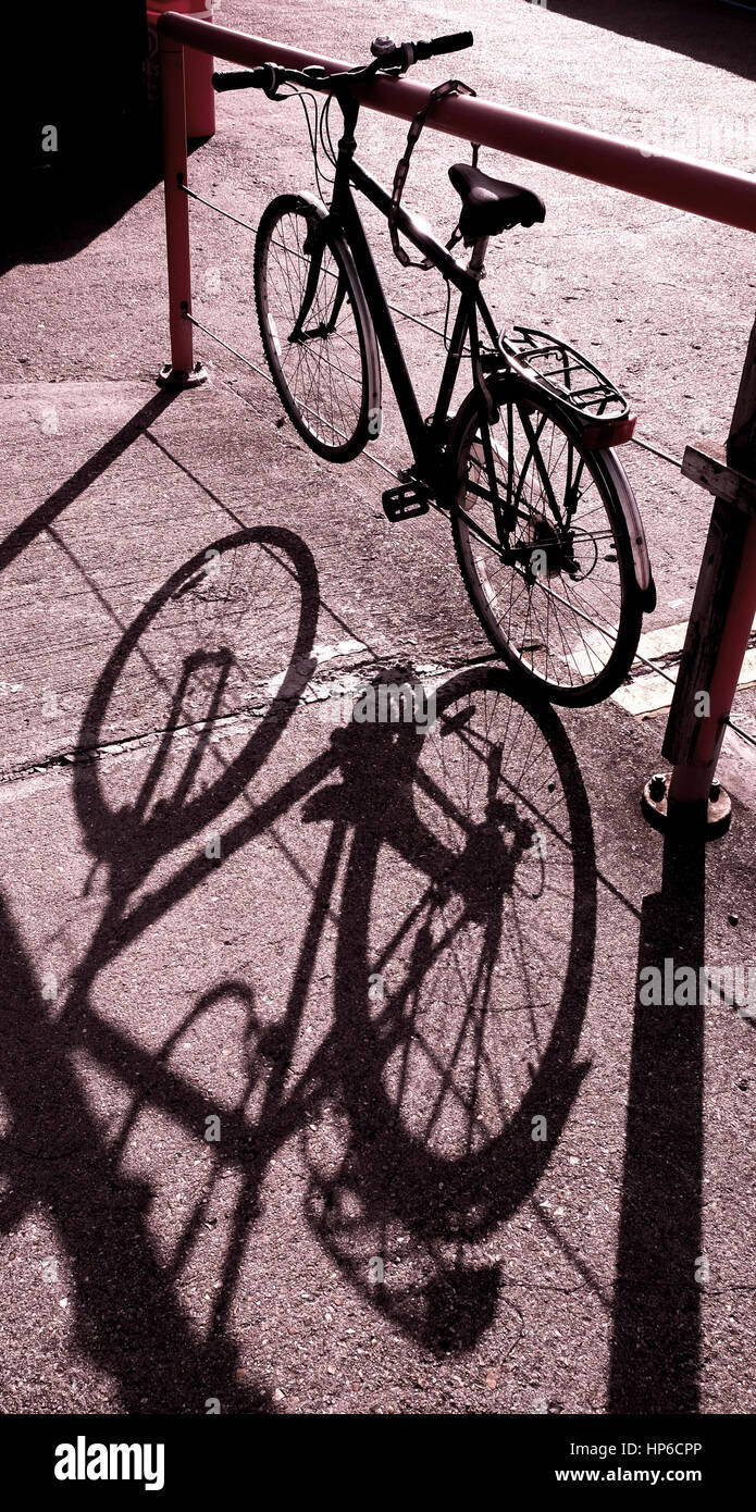 Noleggio legato uo nella luce solare forte di colata ombra di bici sulla massa di calcestruzzo Foto Stock