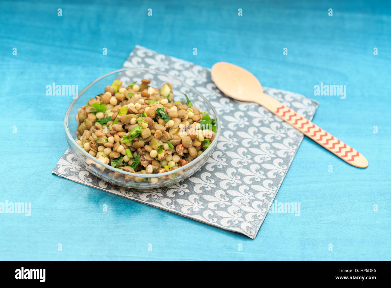 Semplice insalata di lenticchie con sottaceti, il prezzemolo e la pasta sulla tavola turchese sul tovagliolo e cucchiaio rosso Foto Stock
