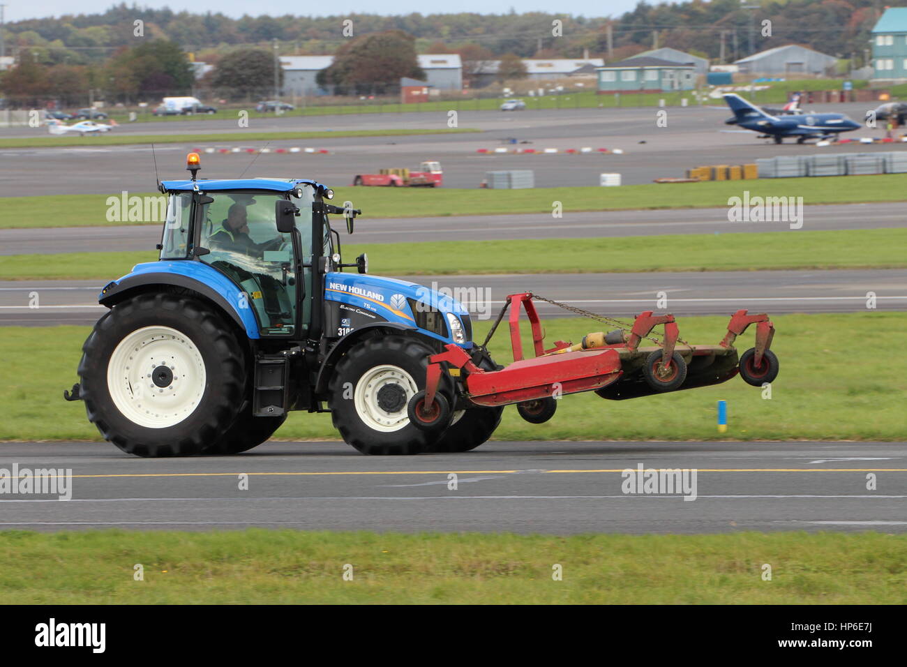 Un New Holland T5.105 elettro utility di comando trattore con annessa la Falciatrice di finitura, a Prestwick International Airport in Ayrshire. Foto Stock