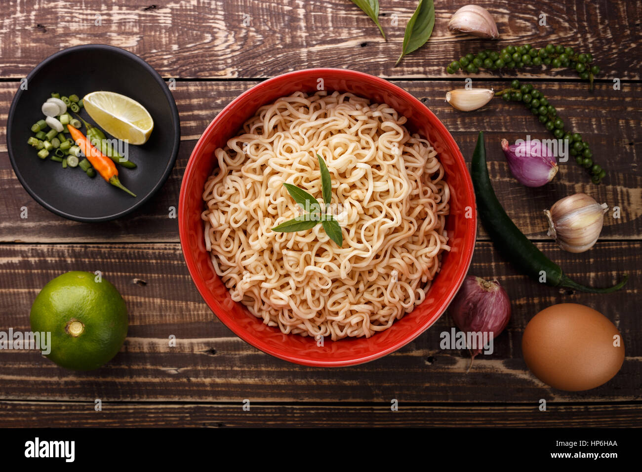 Noodle nella ciotola e ingredienti su uno sfondo di legno vista superiore Foto Stock