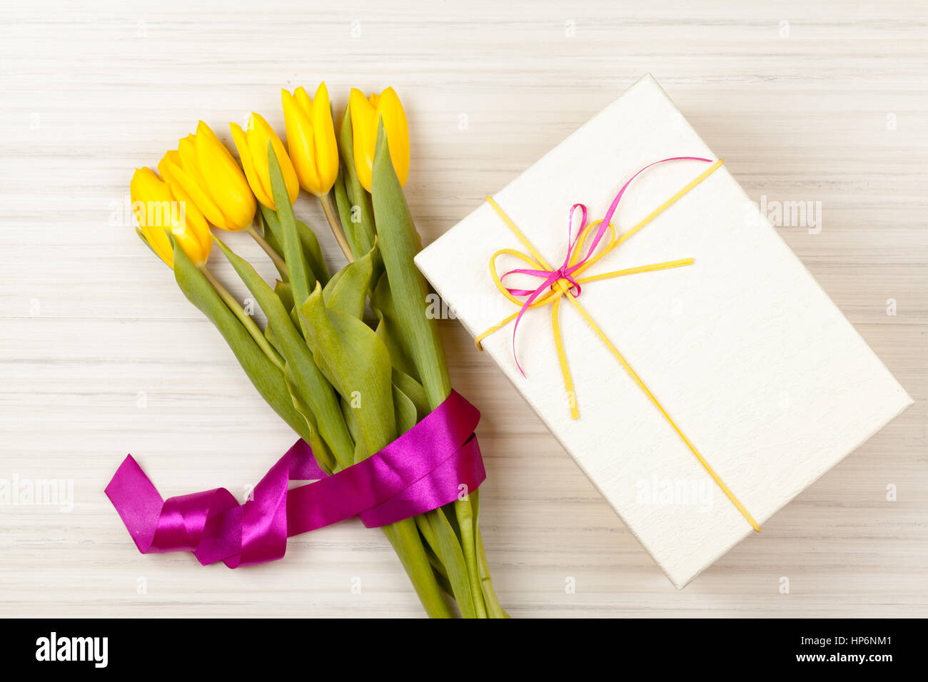 Uova di Pasqua in una scatola con colorati Tulipani gialli e nastro rosa Foto Stock