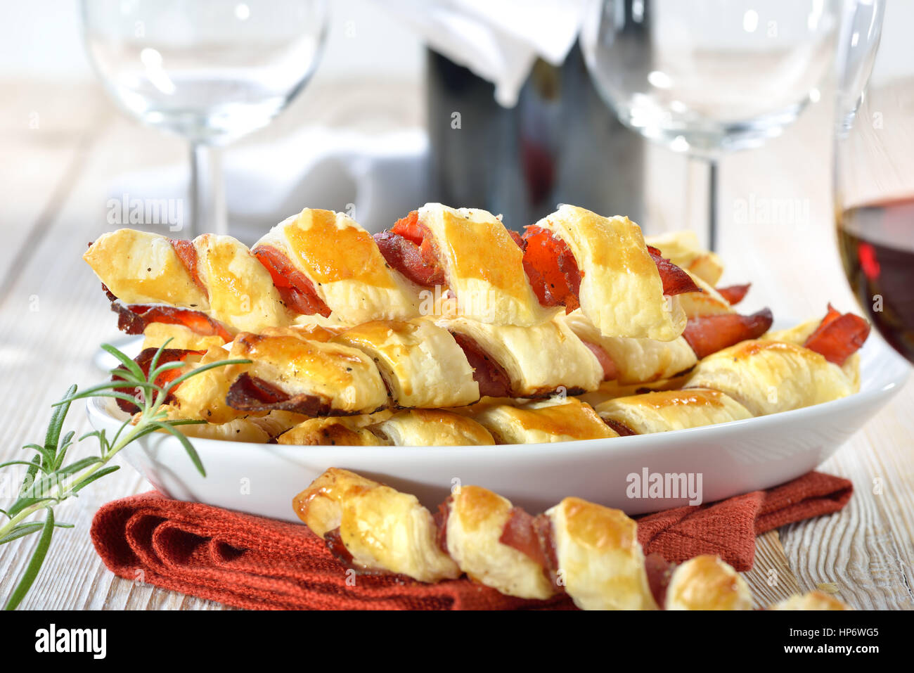 Cotta sostanziosa pasta sfoglia bastoni con prosciutto e erbe aromatiche servita con un bicchiere di vino rosso Foto Stock