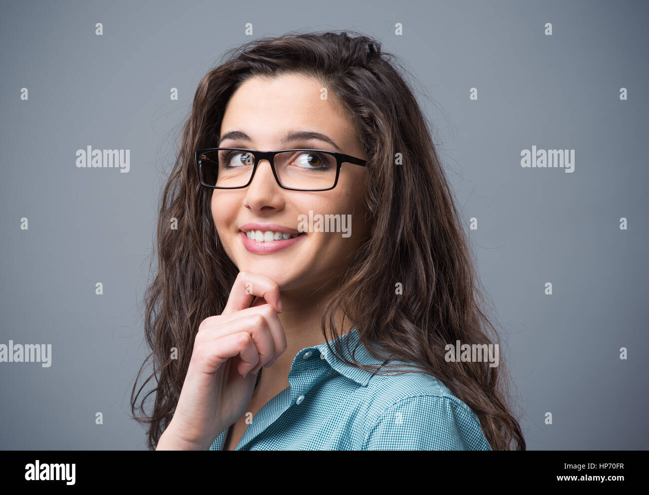 Bella giovane donna pensando con mano sul mento Foto Stock