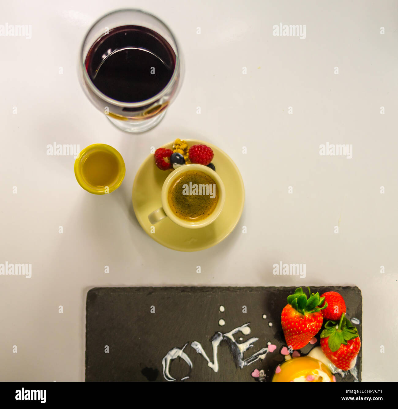 Nero caffè in una tazza di panna con succosa fragola, rasberry set dolce, bicchiere di vino e succo di arancia Foto Stock
