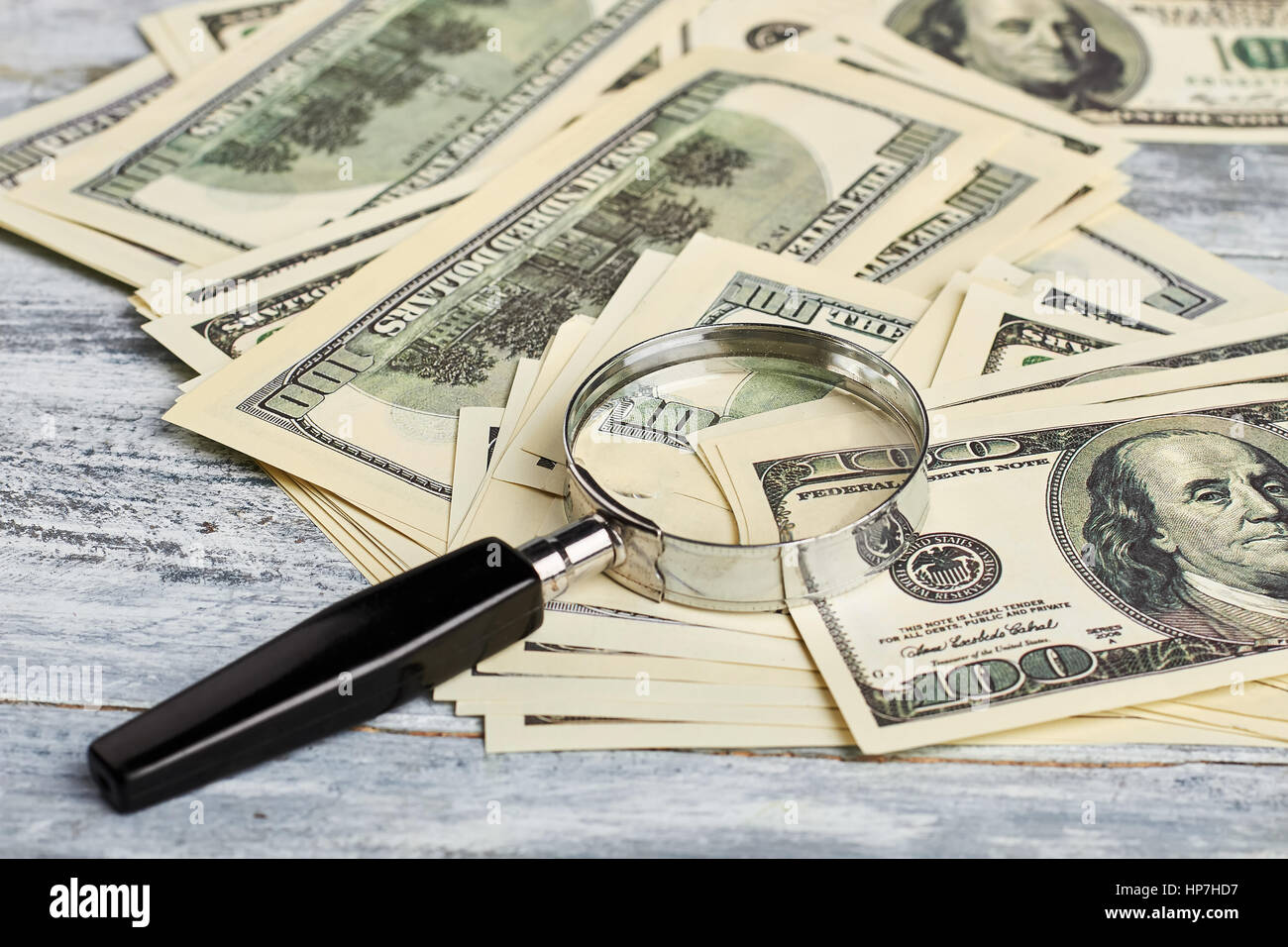 Lente di ingrandimento e dollari americani. Aumentare il vostro reddito finanziario. Foto Stock