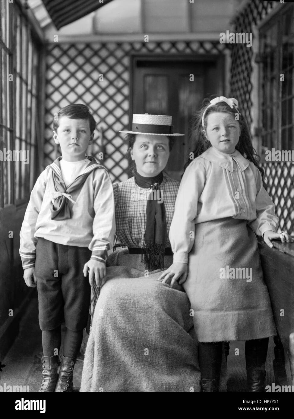 Ritratto di un Edwardian madre accovacciata tra i suoi due figli piccoli, circa 1905, restaurato da una scansione ad alta risoluzione prese dal negativo originale. Foto Stock