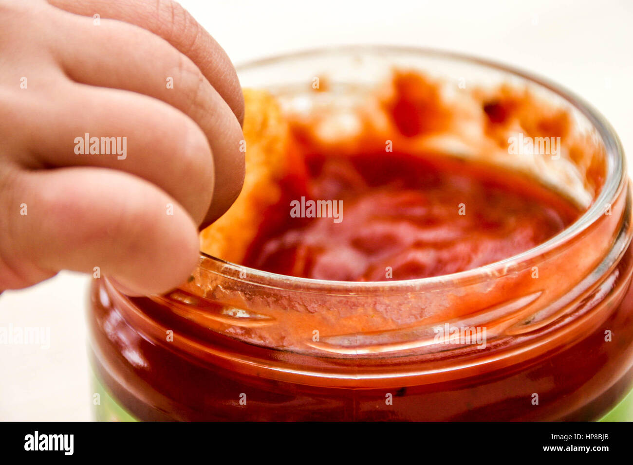Bambino dipping uno snack di mais in salsa di pomodoro dip Foto Stock