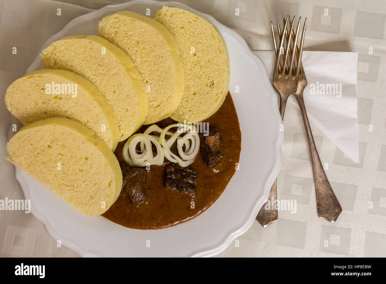 Tradizionale gulasch di manzo con dumplins e cipolla sul tavolo bianco Foto Stock